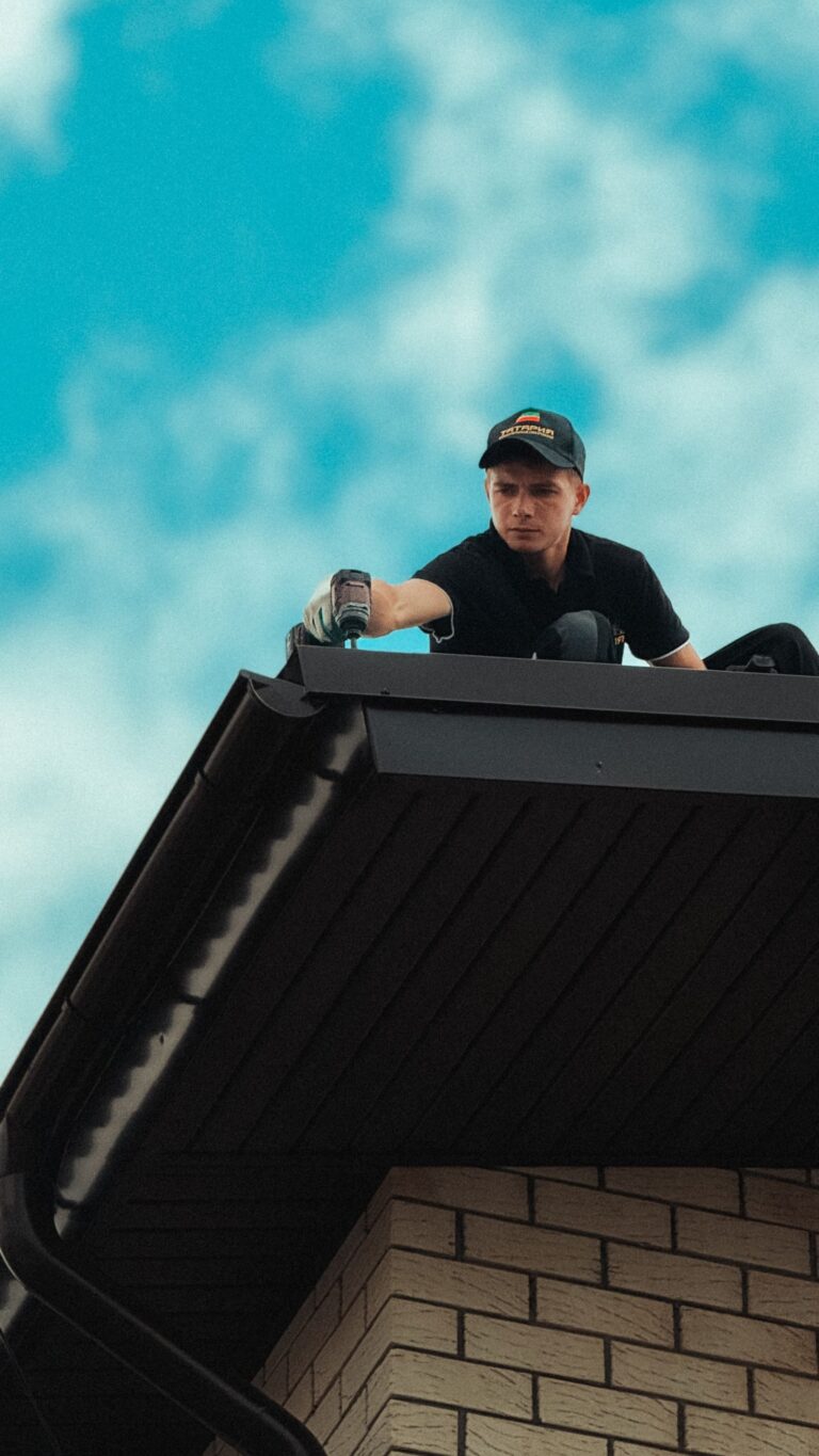 Dakdekker aan het werk op het dak van een huis onder een blauwe lucht
