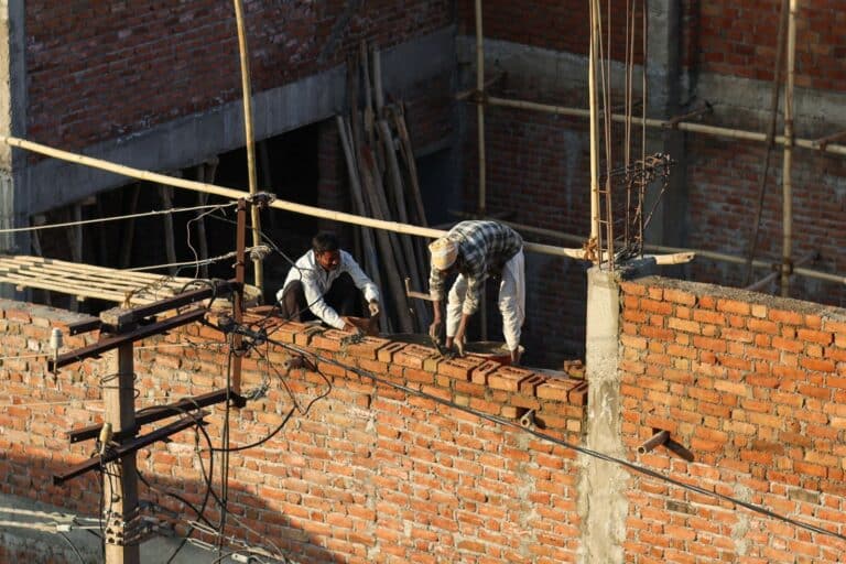 Twee metselaars bouwen een bakstenen muur op de bouwplaats
